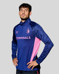Man wearing blue Feyenoord training midlayer top with pink side panels, TERMINALS text across chest and team logos.