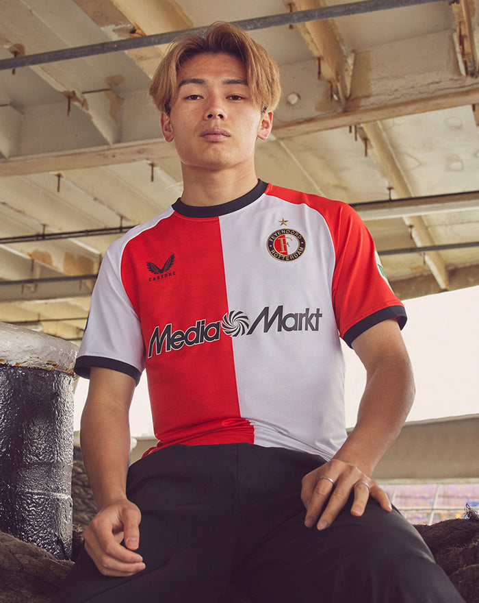 Male model wearing Feyenoord 2024-2025 home shirt with red and white split design, crest on the left chest and MediaMarkt logo across the front