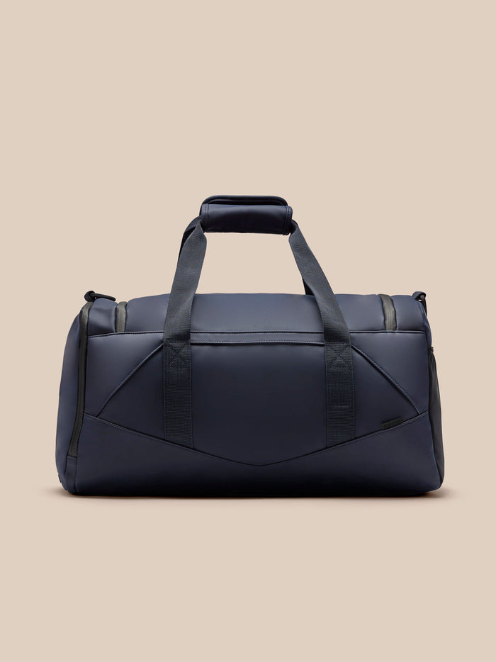 Navy Core Holdall shown from a front angle with top handles and crossbody strap, logo on the front.