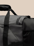 Close-up of the holdall strap and top edge showing durable black webbing and a padded carry handle.