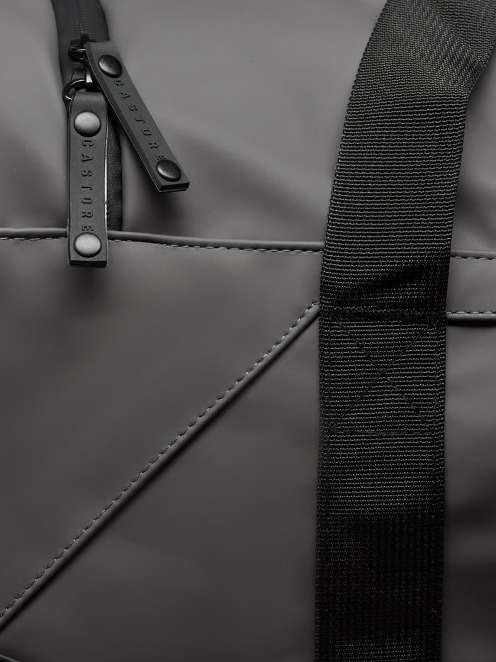 Close up of gunmetal Core Holdall with black strap and branded zipper pulls