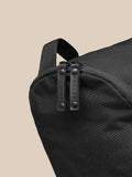 Close up of a black boot bag showing dual zipper pulls embossed with CASTORE on textured fabric