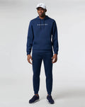 Volledig lichaam van model in donkerblauwe Active Flex hoodie met bijpassende joggers en witte pet.