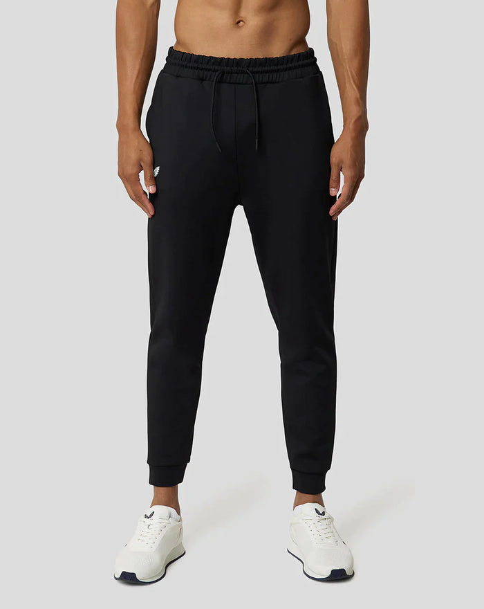 Model draagt zwarte Ore Capsule joggingsbroek met trekkoord en subtiele branding, witte sneakers.