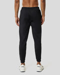 Back view of a man wearing black Ore Capsule Jogging pants with an elastic waistband and white sneakers.