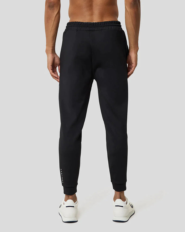 Back view of a man wearing black Ore Capsule Jogging pants with an elastic waistband and white sneakers.