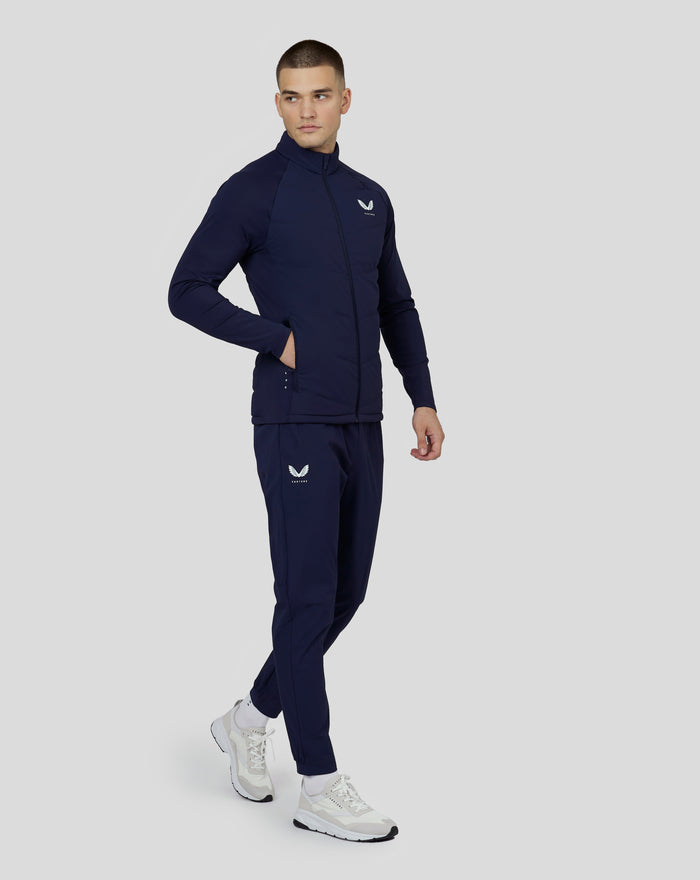 Male model wearing a navy Castore quilted zip jacket with a high collar and chest logo.