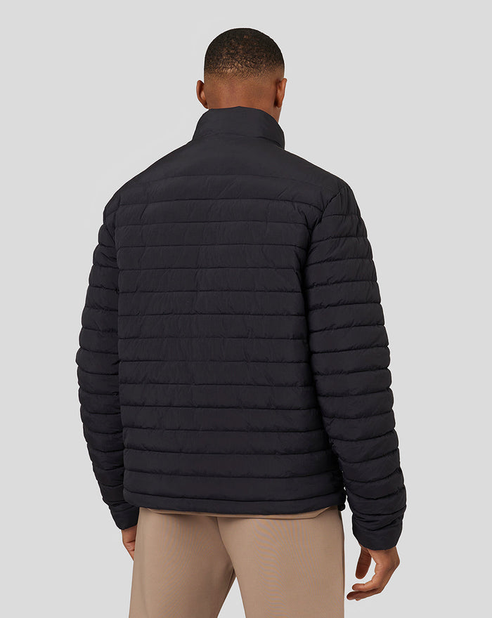 Back view of a man wearing a black Castore lightweight puffer jacket with horizontal quilting