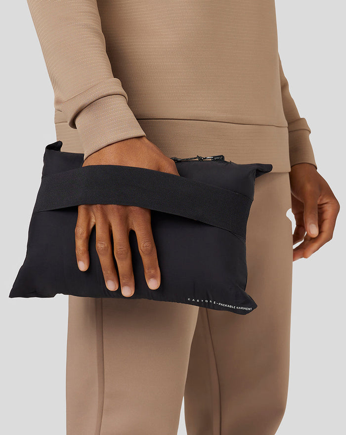 Close up of a hand holding a black packable garment pouch with a wide strap