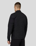 Back view of a man wearing a black Castore Zone Hybride Jacket with quilted chevron panels.