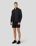 Male model wearing black Castore Zone Hybrid Jacket with reflective details and padded panels