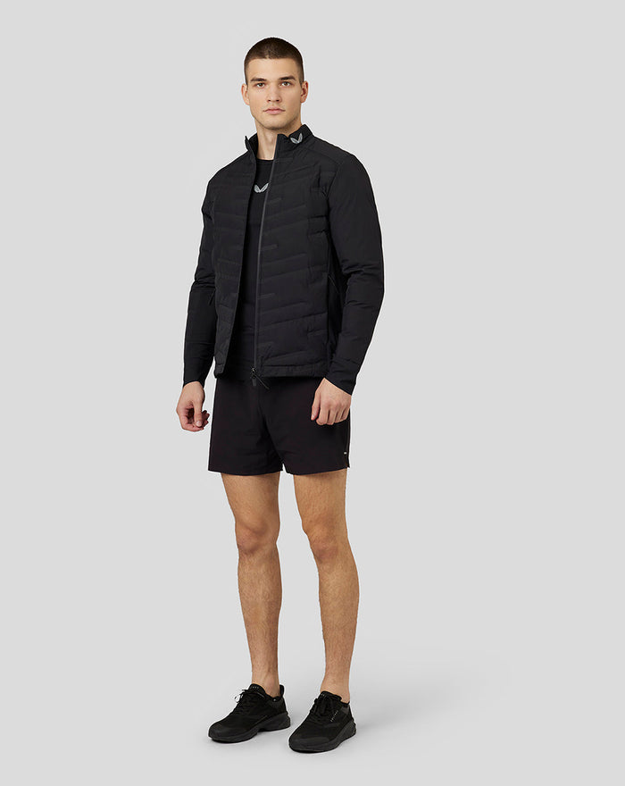 Male model wearing black Castore Zone Hybrid Jacket with reflective details and padded panels