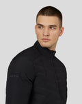 Front three-quarter view of a man in a black Castore Zone Hybride Jacket with stand collar and reflective collar details.