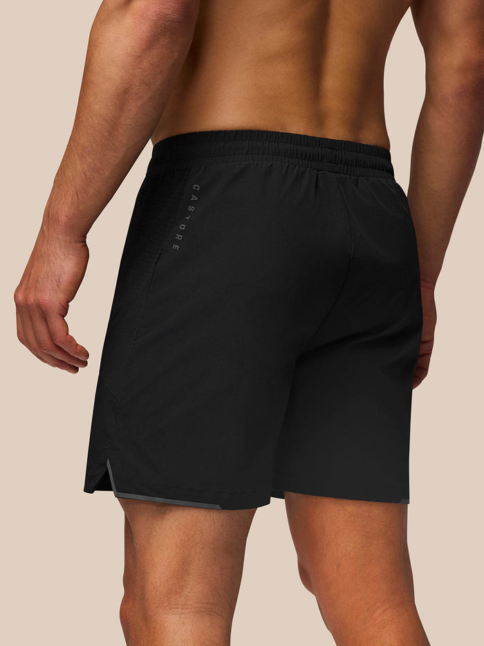 Back view of a man in black Apex Geweven Short with reflective Castore branding along the left leg