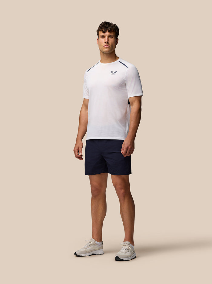 Full-body view of a male model wearing navy Apex Aeromesh shorts and a white top