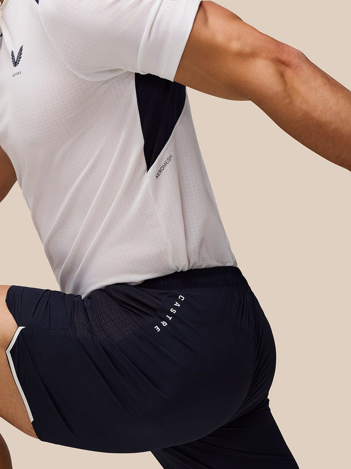 Apex Aeromesh 6 inch navy shorts with zip pockets and reflective Castore logos on the right thigh worn by a male model