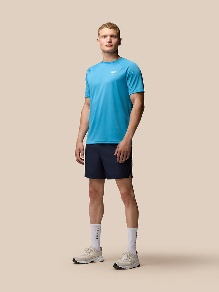 Male model wearing a bright blue athletic T shirt and navy Adapt 6 inch stretch woven shorts