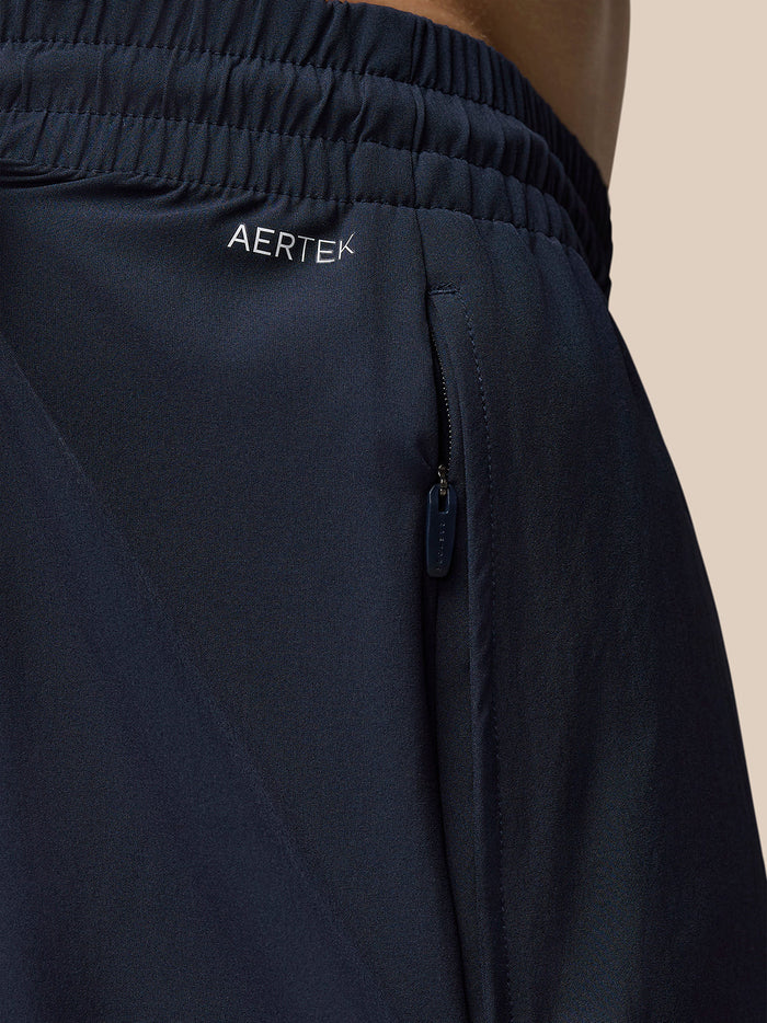 Close up of navy Adapt 6 Stretch woven shorts with elastic waistband side zip pocket and Aertek branding