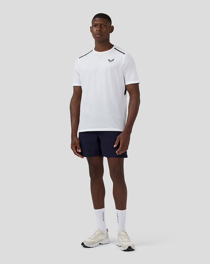 Front view of a male model in a white Apex Aeromesh T-Shirt with navy shoulder panels and a Castore logo on the left chest