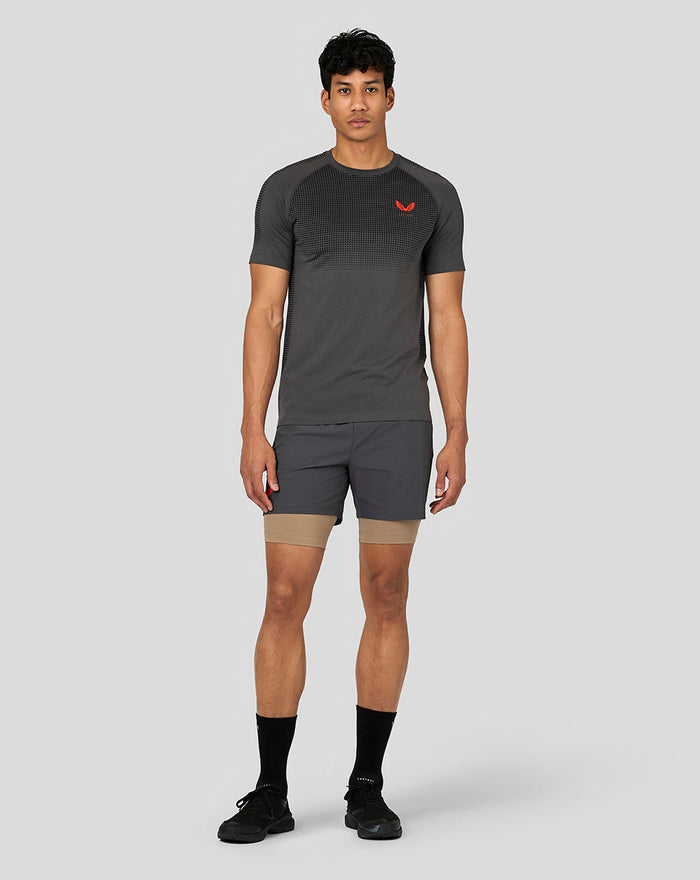 Volledig lijf model in donkergrijze Castore Flow trainings T-shirt met gebreide borstpanelen en rode borstlogo.