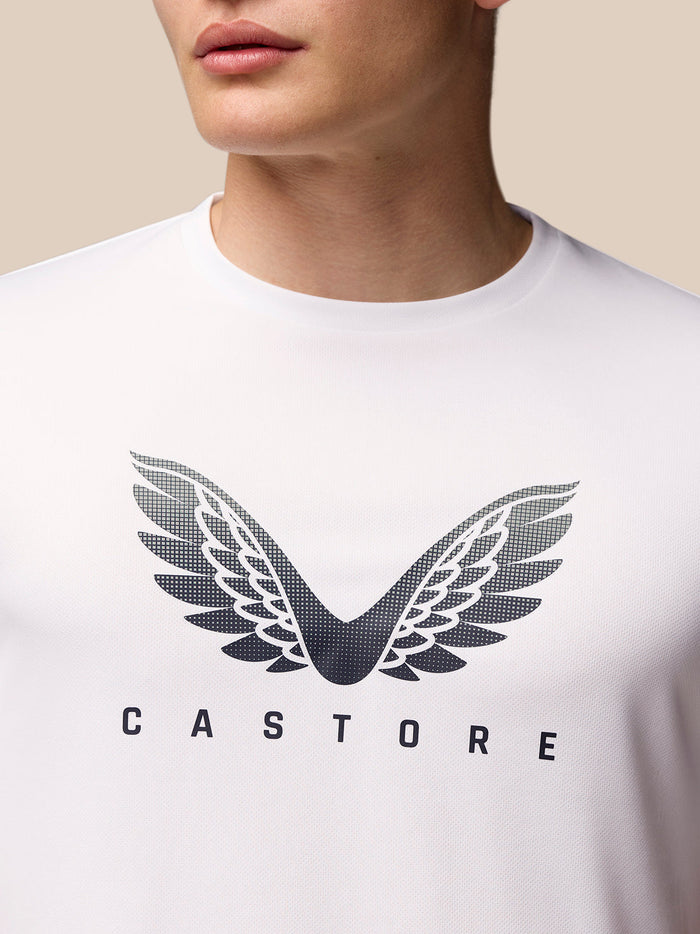 Male model wearing white Adapt Short Sleeve Graphic T Shirt with wing logo on chest and black shorts