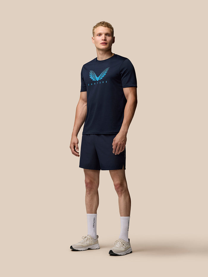 Herenmodel in marineblauw Adapt Graphic T-Shirt met vleugellogo op de borst en bijpassende marineblauwe shorts