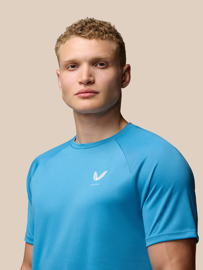 Front view of a male model wearing blue Adapt T Shirt with a small Castore logo on the left chest.