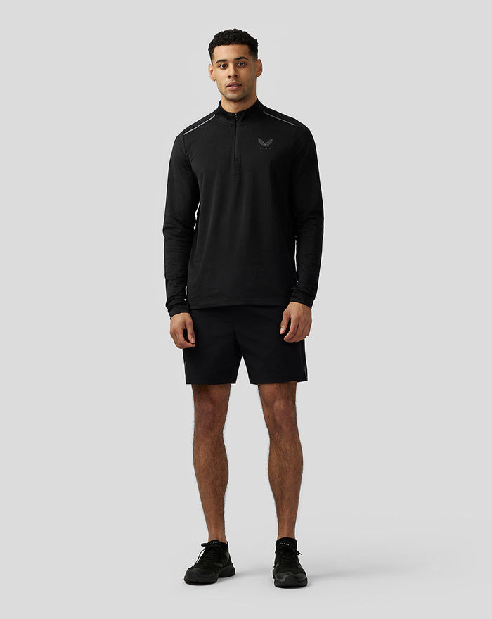 Model draagt zwarte Apex Aeromesh Top met kwartrits en lange raglanmouwen gecombineerd met zwarte korte broek