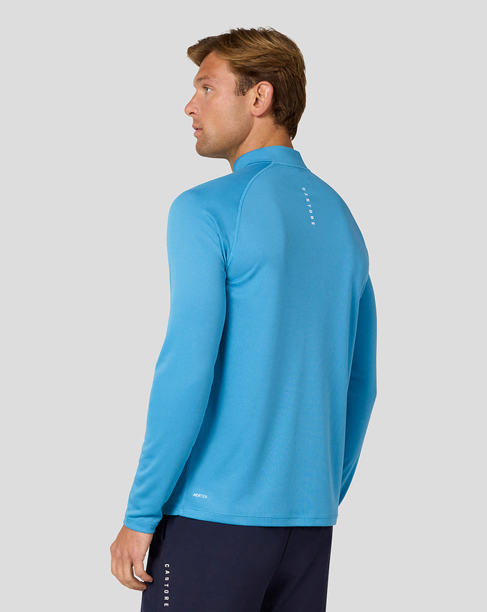 Back view of blue long sleeve top on male model showing Castore logo down the spine.