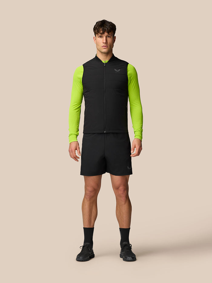 Man wearing Apex Training Gilet in black with neon lime sleeves, full front zip, and reflective Castore logo on the left chest.