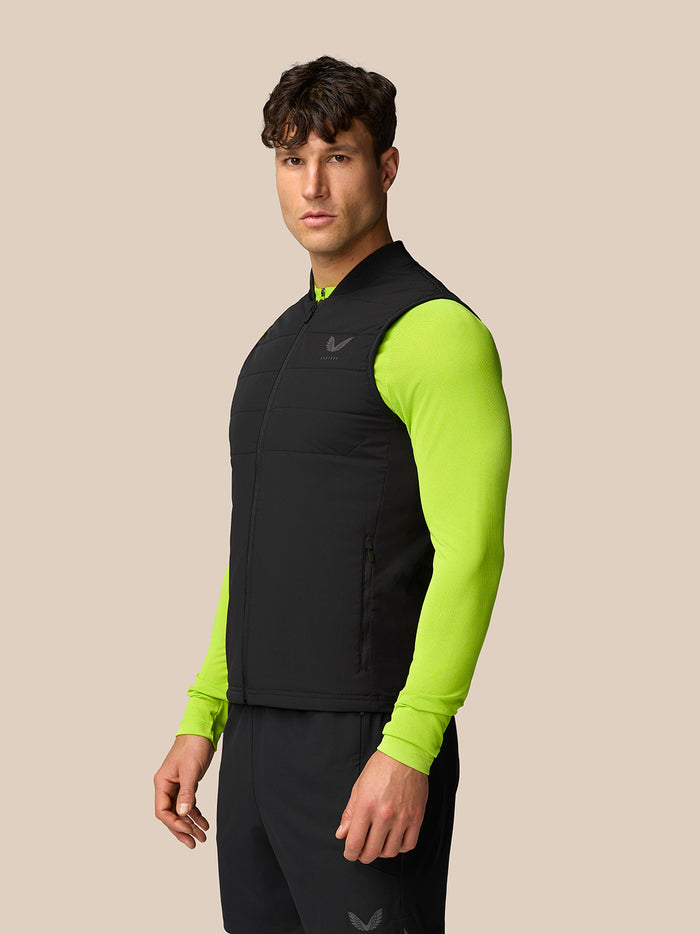 Side view of a man in black Apex Training Gilet with neon lime sleeves, showing the sleeveless vest over bright sleeves and zip pockets.