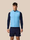 Apex Training Gilet in lichtblauw gedragen door mannelijke model, mouwloos gewatteerd vest met ritssluiting en Castore-logo op de borst