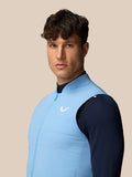 Front view of a man wearing a light blue Apex Training Gilet over a navy top with Castore logo on the chest.
