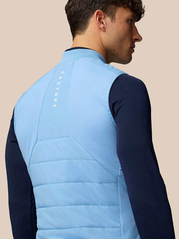 Back view of a man wearing a light blue Apex Training Gilet with a vertical Castore logo along the back.