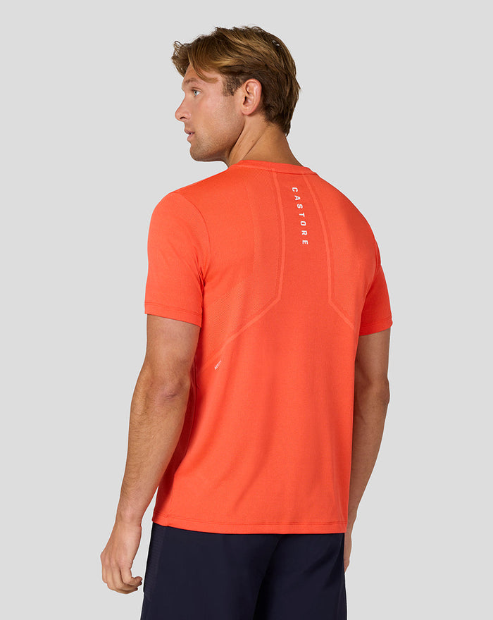 Back view of a bright orange Castore Apex Engineered Knit T Shirt for men with a reflective logo on the upper back