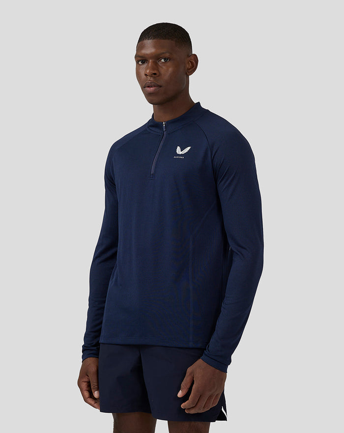 Male model wearing navy long sleeve Apex engineered woven top with a stand-up collar and front zipper, Castore logo on left chest.