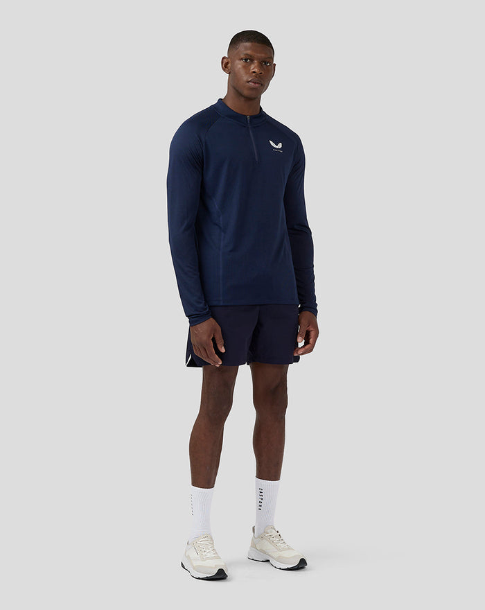 Male model in navy long sleeve athletic top with a zip collar and Castore branding on the left chest.