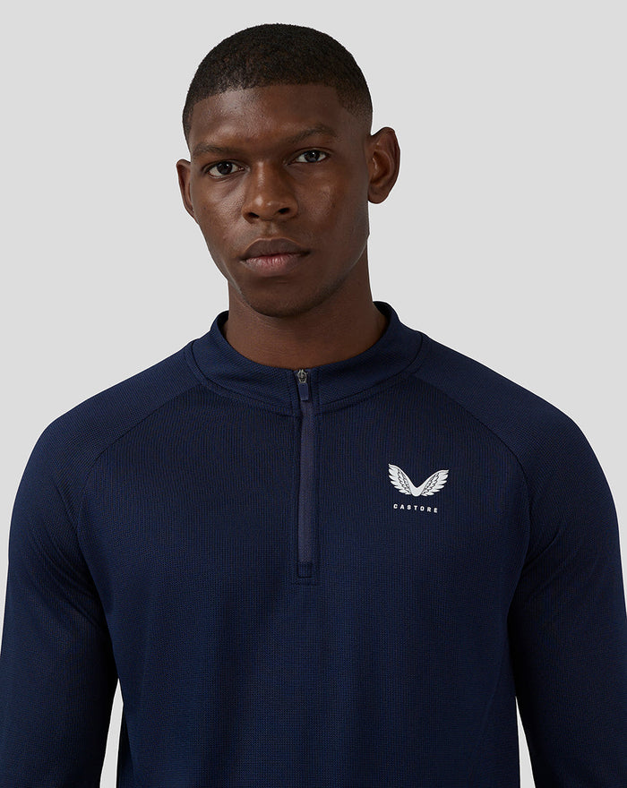 Close-up of navy long sleeve top showing white Castore logo on the left chest.