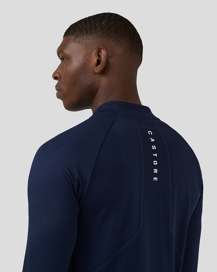 Back view of a man wearing navy long sleeve athletic top with a vertical Castore branding down the back