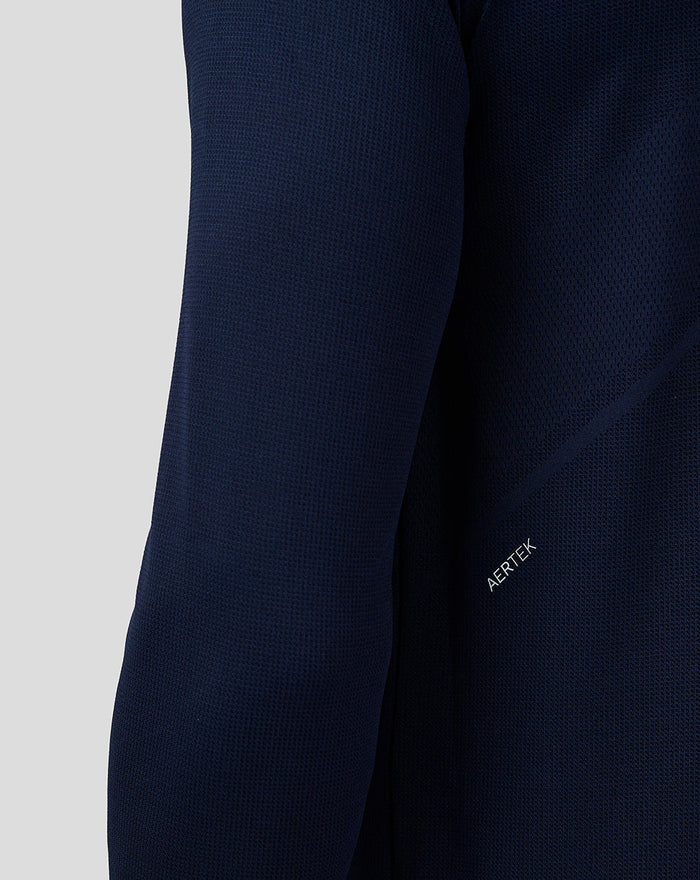 Close-up of navy fabric from the Apex top showing a textured knit and the AERTEK label