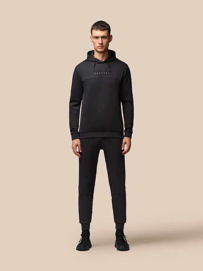Full-body shot of a man in a black Flex Hoodie and matching joggers with CASTORE logo on the chest