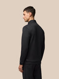 Side view of male model in black Flex Quarter Zip Top with front zipper and zip pockets; Castore logo on left chest.