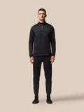 Full-body view of a man in a black Flex Quarter Zip top with matching pants, Castore branding on the chest.