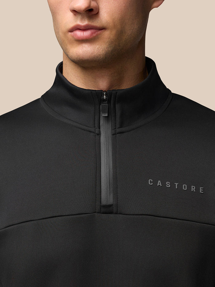 Close-up of a black Flex Lifestyle Top with a high collar and quarter zip, Castore logo on the left chest.