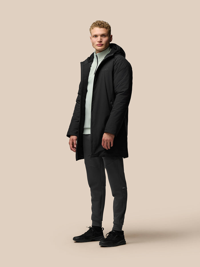 Male model in a black longline jacket with hood over a mint green zip pullover