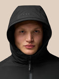 Model draagt een zwarte langejas met capuchon en zichtbare Castore rits.