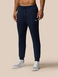 Back view of a man wearing navy Travel Lifestyle Joggers with a drawstring waist and logo on the leg.
