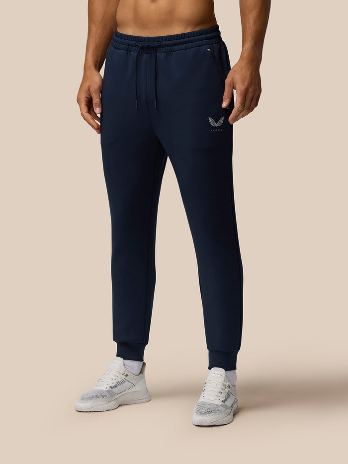Back view of a man wearing navy Travel Lifestyle Joggers with a drawstring waist and logo on the leg.