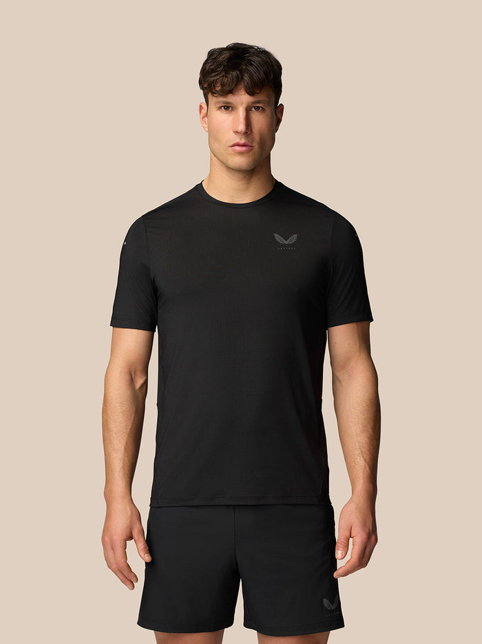 Zwarte Apex Training T-Shirt met ronde hals en reflecterend Castore-logo gedragen door een man tegen een neutrale achtergrond.