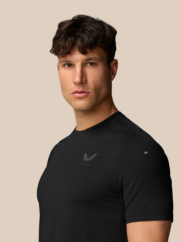 Angled front view of man in black Apex Training T-Shirt showing chest Castore logo and reflective sleeve detail